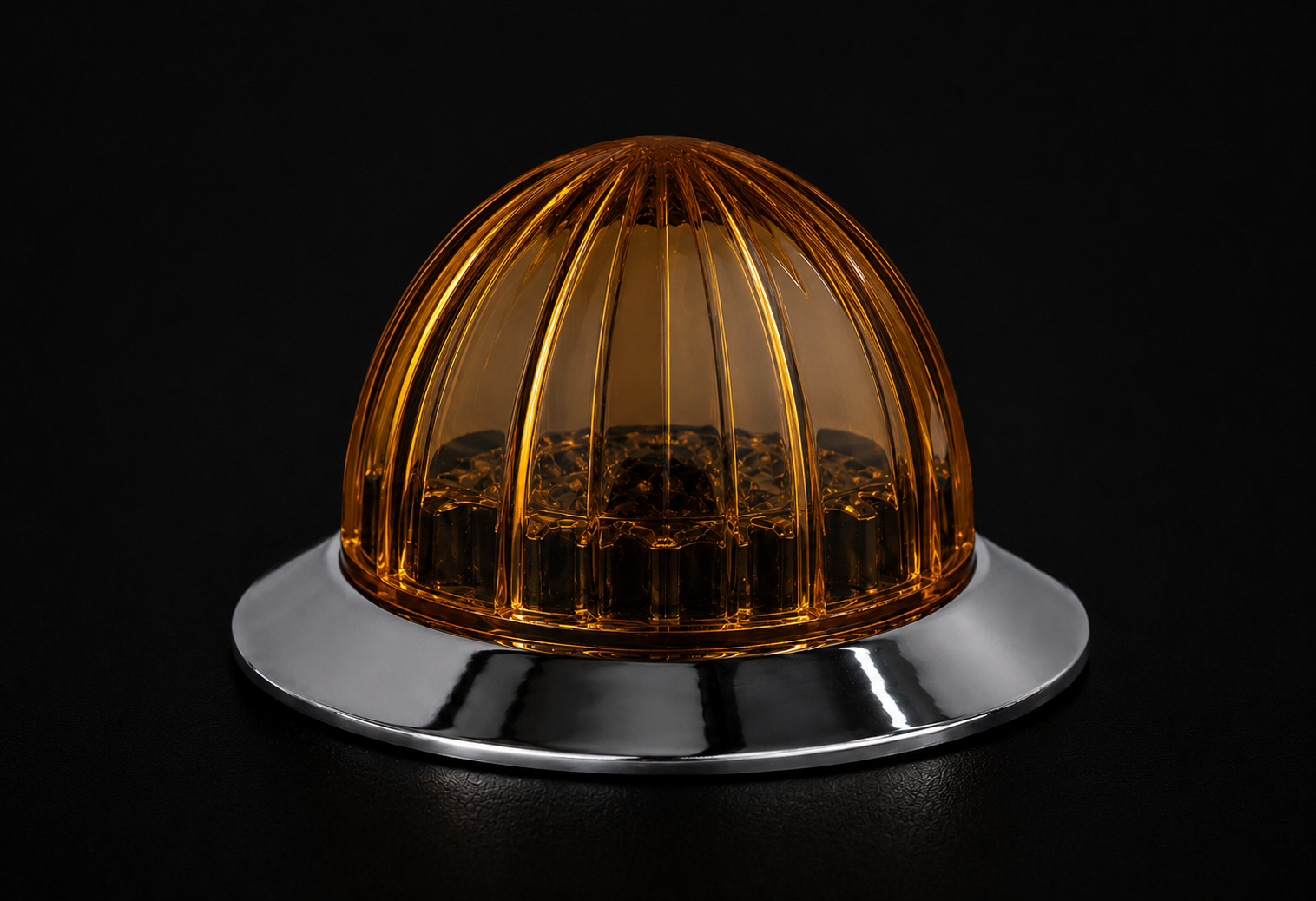 Amber-colored dome-shaped object on a reflective silver base against a black background